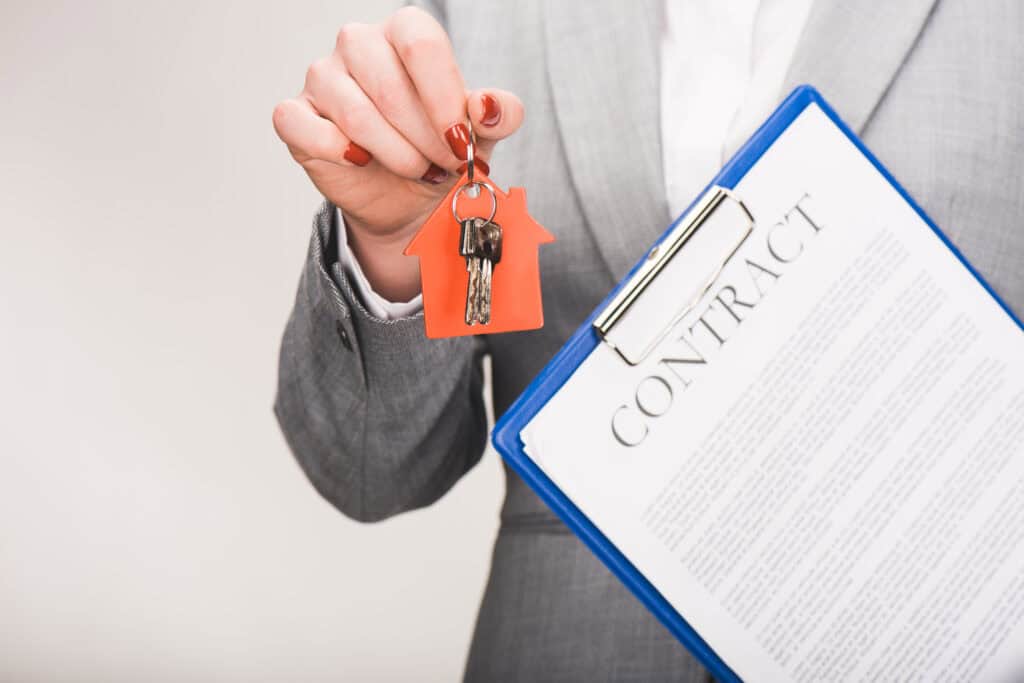 cropped image of estate agent holding keys and contract