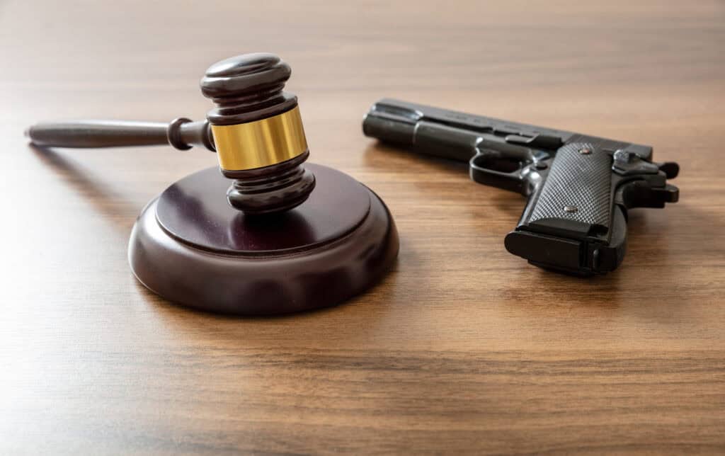 Judge gavel and handgun on lawyer office desk