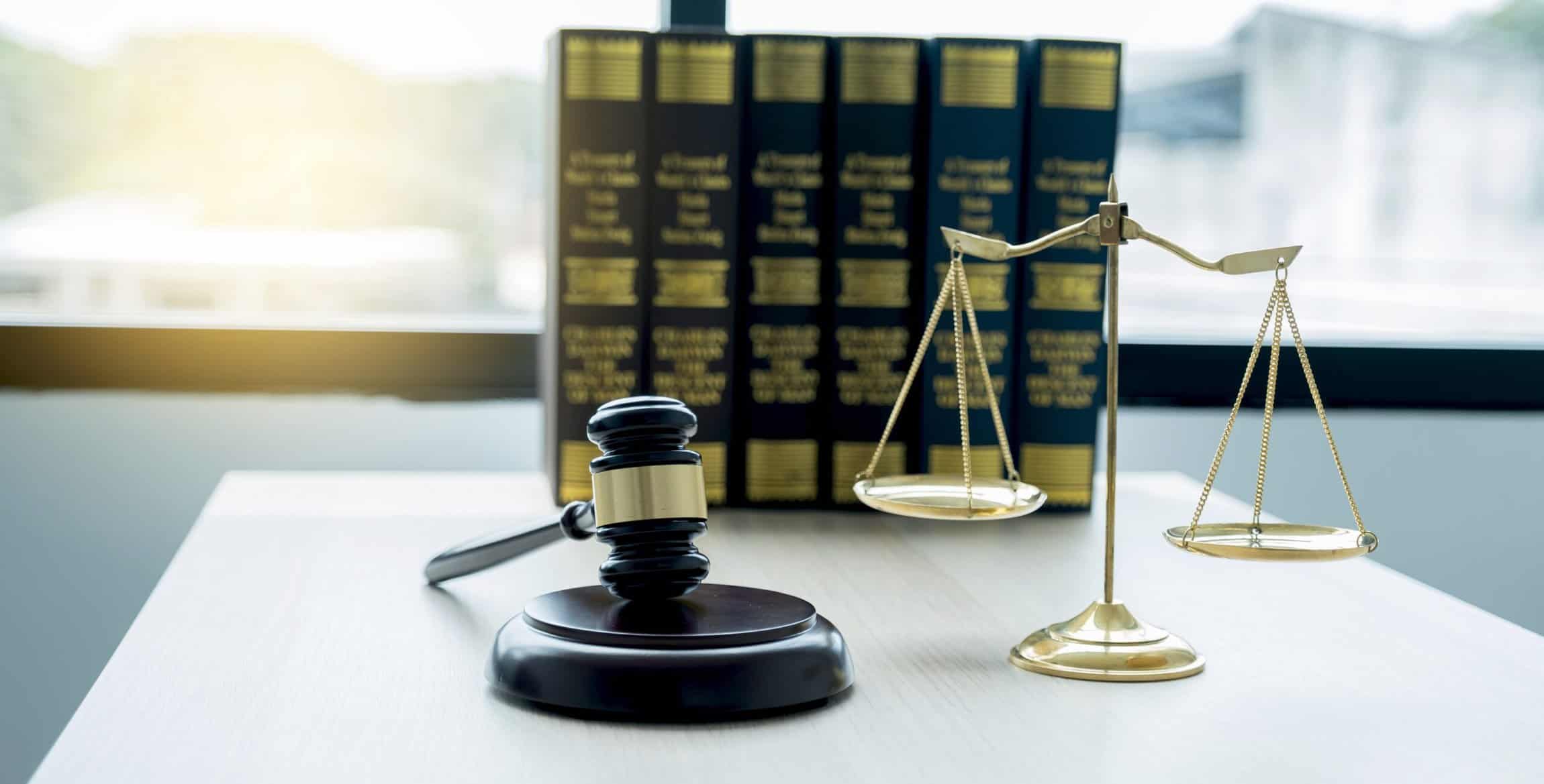 Gavel hammer, justice scale, and law textbook on table in lawyer office for providing legal consult business dispute service.