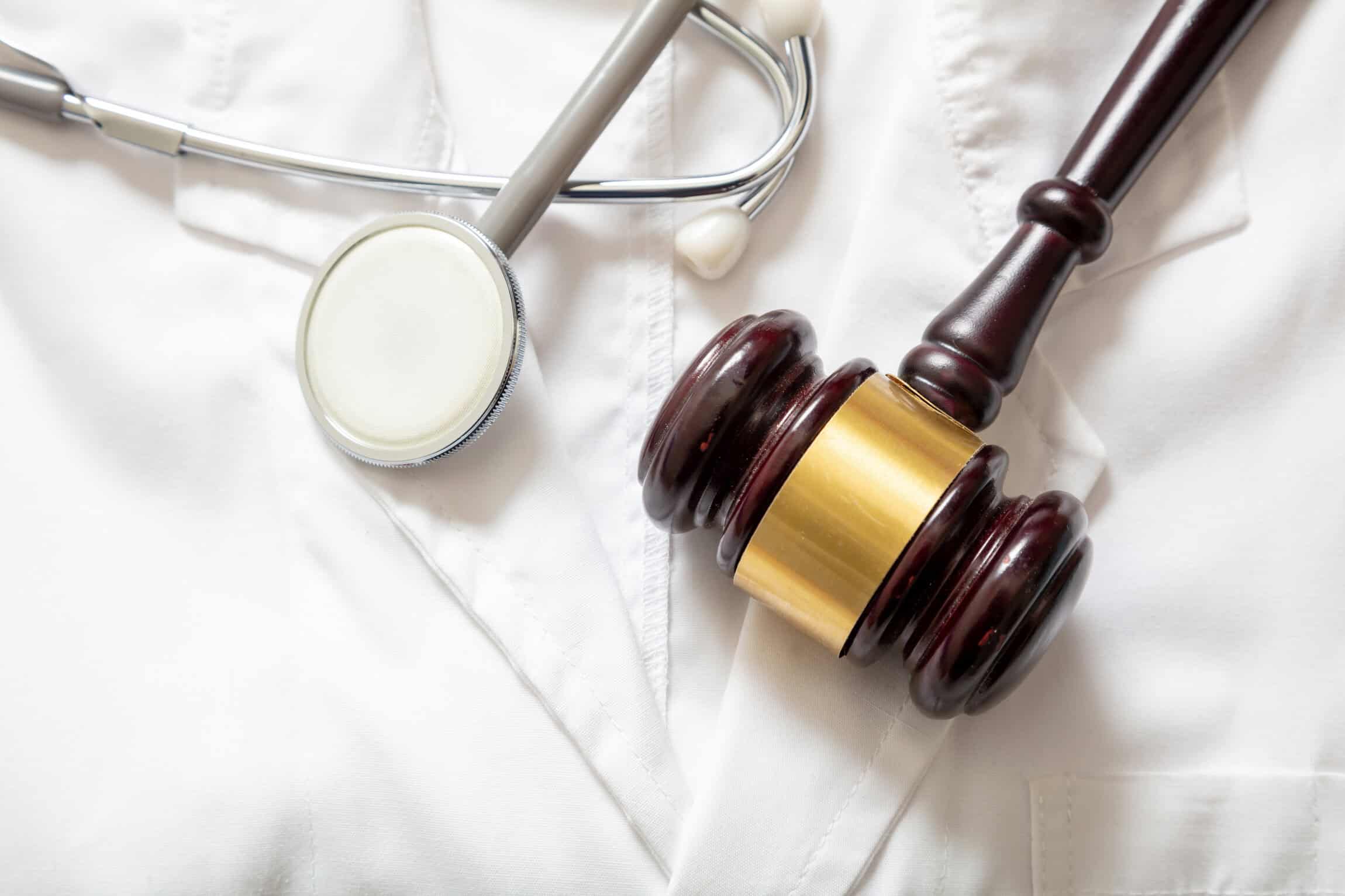 Judge gavel and stethoscope on doctor coat, top view