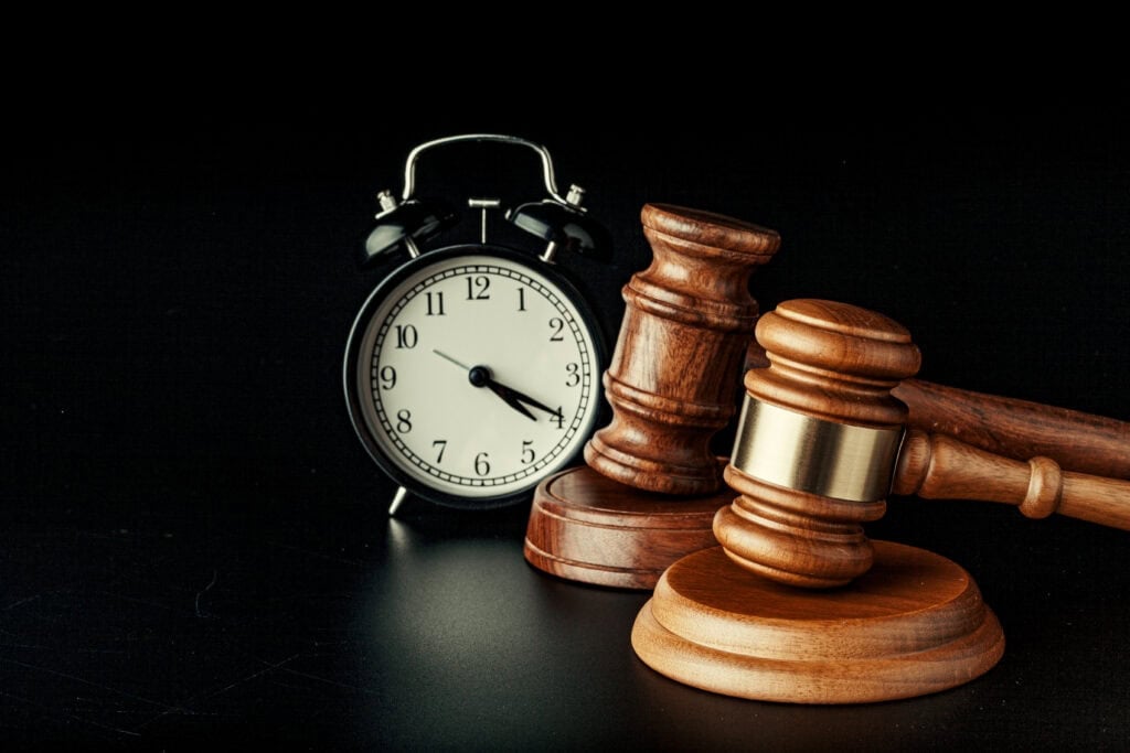 Wooden judge gavel with clock on black background