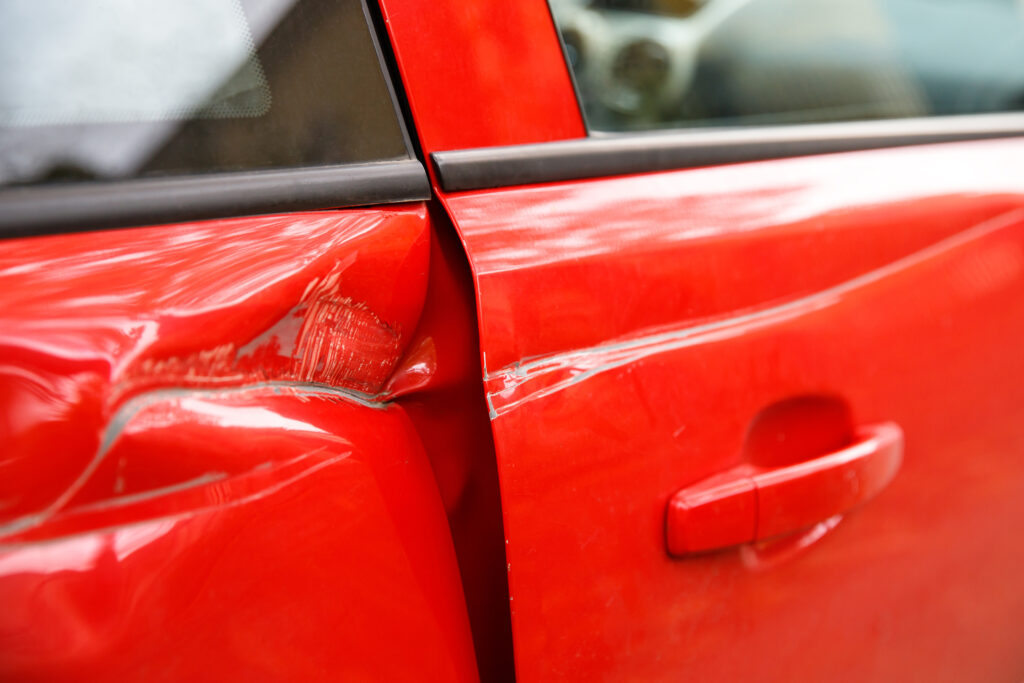 Door red car damaged in a deep dent accident, scratches on the doors. uninsured motorist coverage lawyer concept