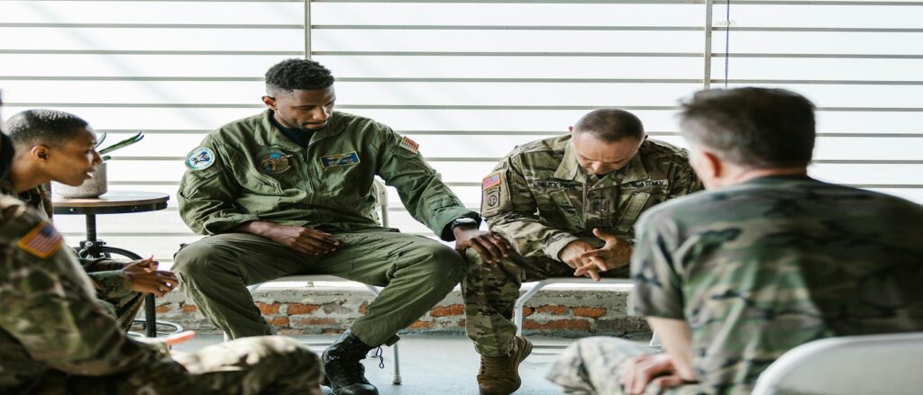 Picture of uniformed military men sitting talking associated with blog on personal injury Tricare liens