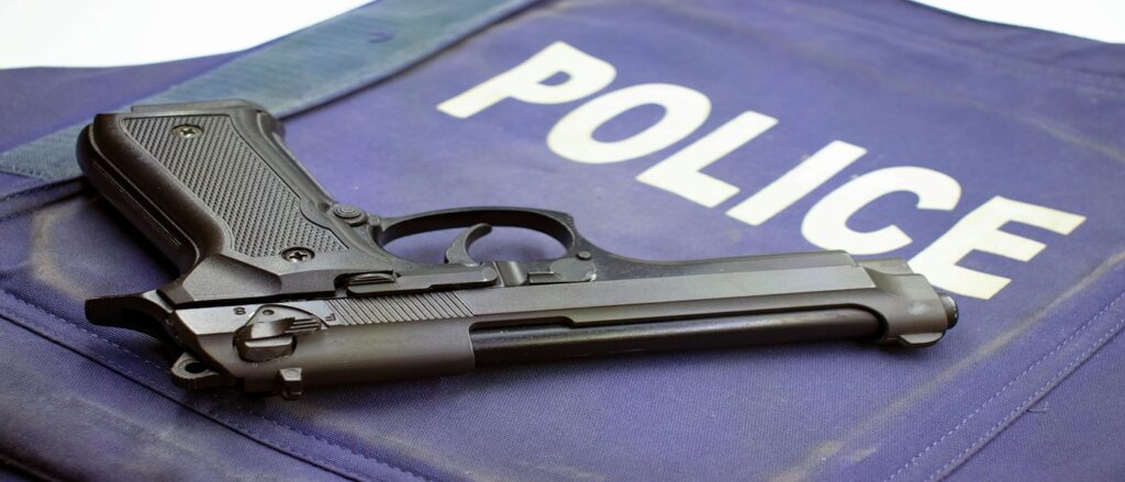 Picture of handgun on mat with word police in background associated with blog on police use force causing personal injury qualified immunity